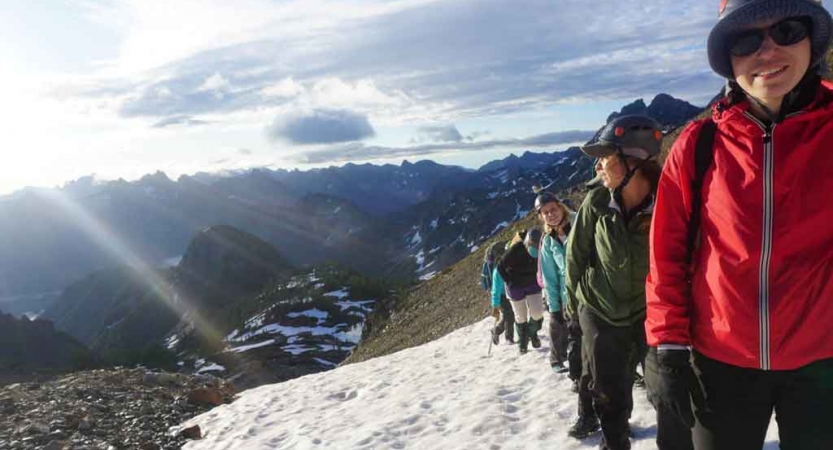 a group of women ascend a snowy trail on a mountaineering course with outward bound